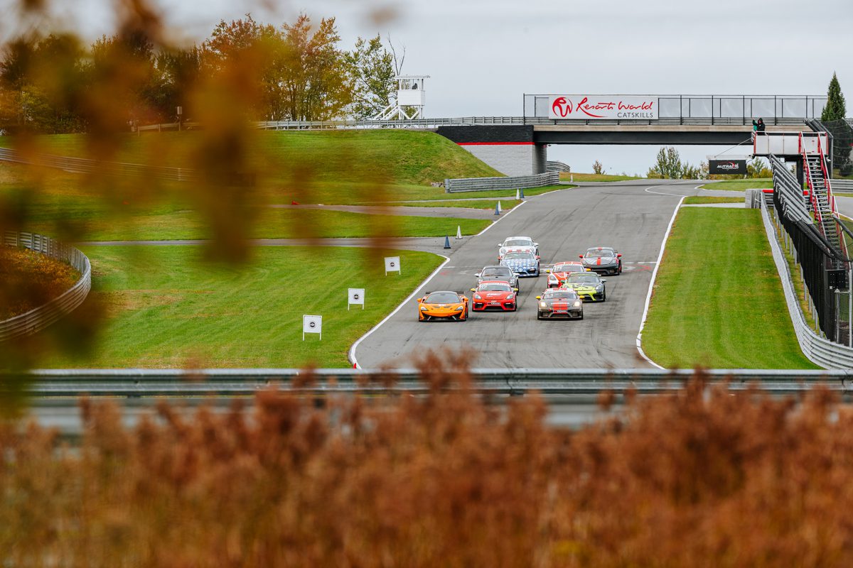 A group of race cars are racing down the straight away