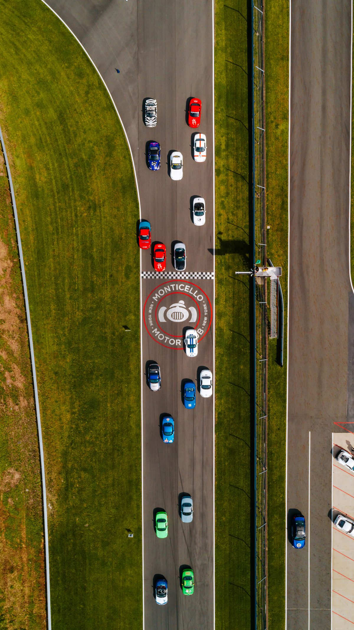 a top-down aerial view of the race track as many race cars race by