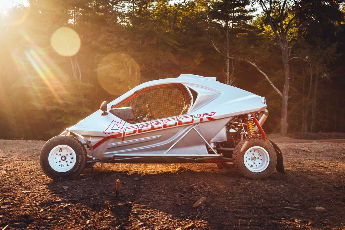 A silver cross kart parked in the dirt during sunset