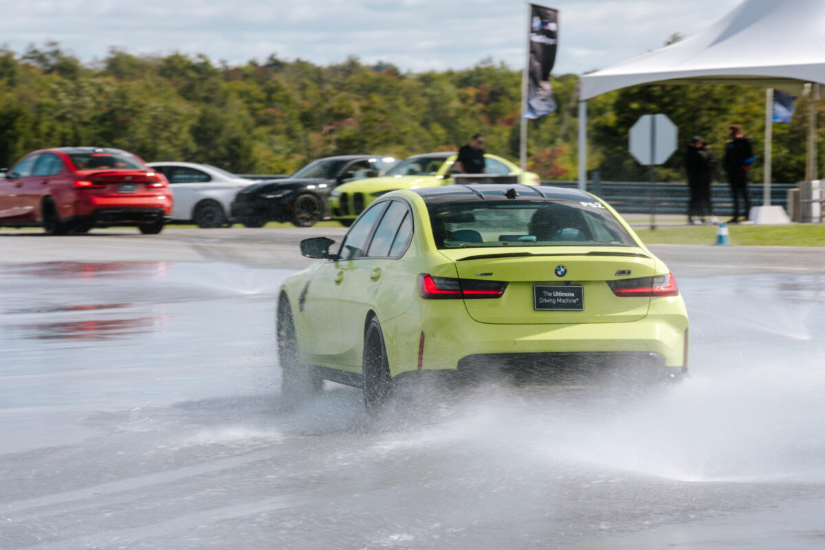 A yellow/green BMW M3 Competition drifts on the wet skid pad