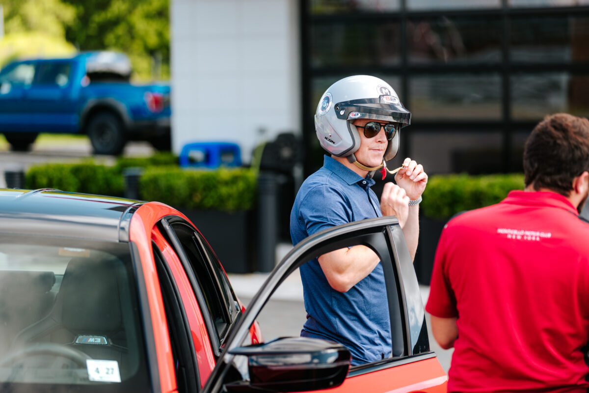 A male wearing sunglasses and a helmet is getting out of a vehicle