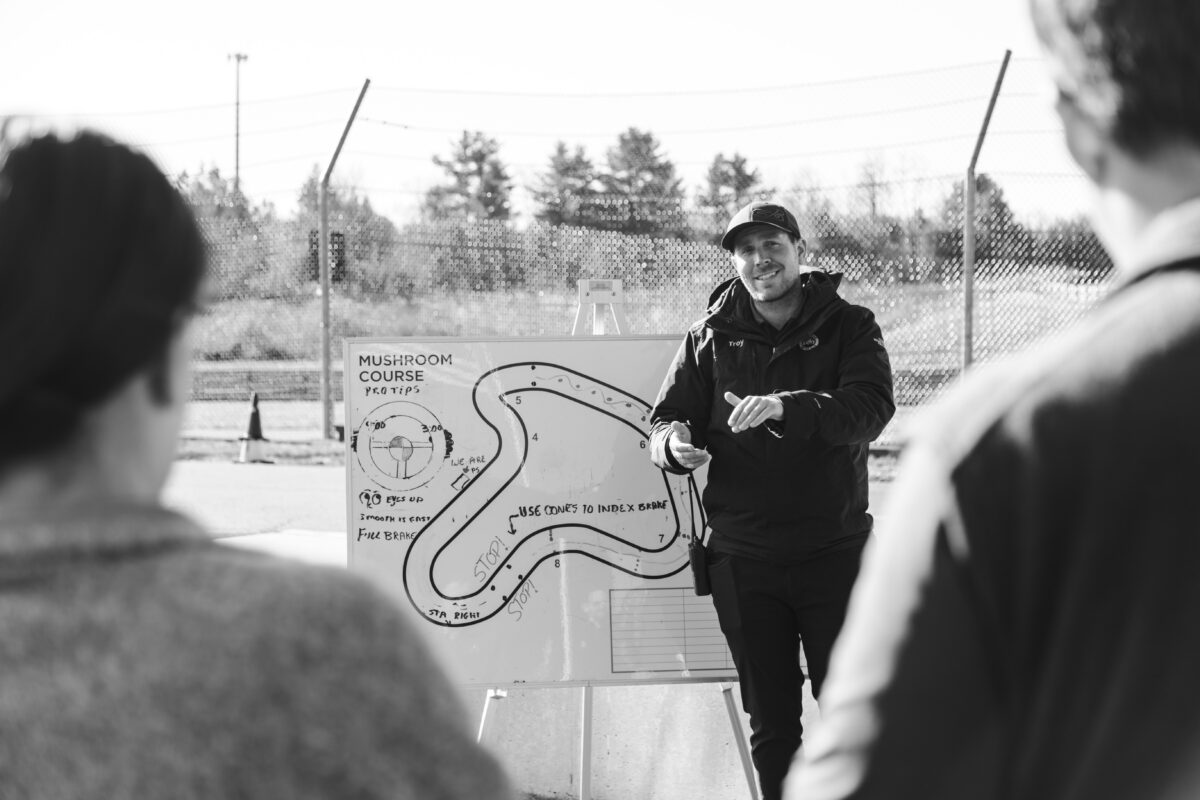 an instructor is standing next to a track map explaining information to guests