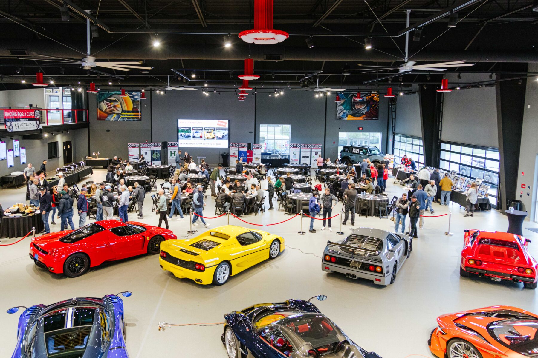 Large charity event inside MMC's gallery with exotic cars in the foreground and guests in the background