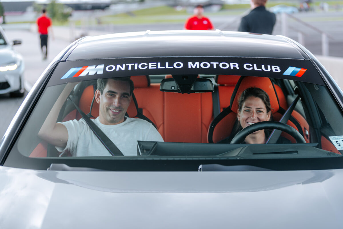 A man and woman are sitting in a gray BMW smiling through the windshield