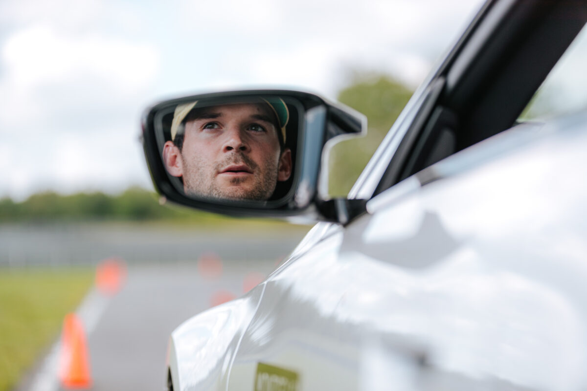 A white male looks in the rear view mirror