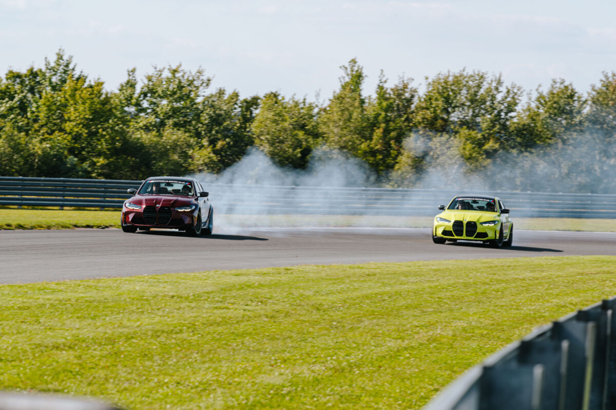 two bmw m3s are drifting through a turn together